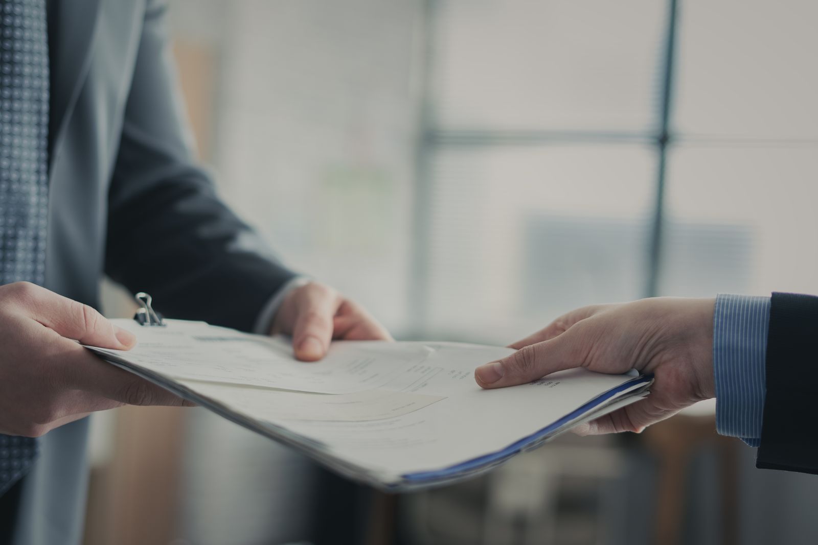Legal papers being handed from one person to another